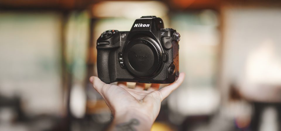 A person indoors is engrossed in adjusting settings on a Nikon Z series camera, effectively creating an auto draft of their next photographic masterpiece.