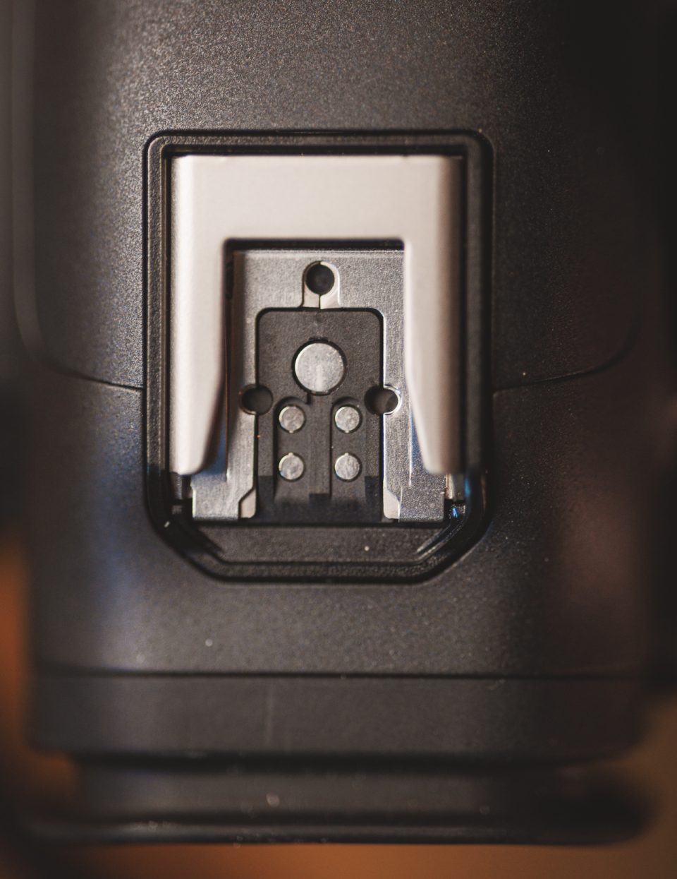 Close-up image of a camera's metal hot shoe mount used for attaching accessories like flashes or microphones, showcasing its durability and real-world use in the Canon R5 Mark ii Review.